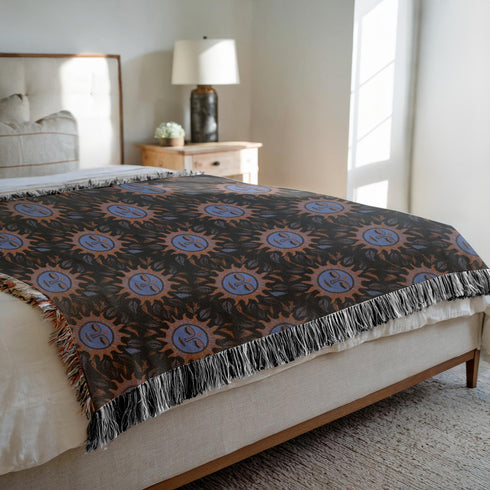 Luxurious woven cotton throw blanket featuring mystical blue sun faces with copper rays on black background, bordered by elegant fringe. Perfect celestial wall hanging, witchy bedroom decor, or dark academia throw for couch or bed.
